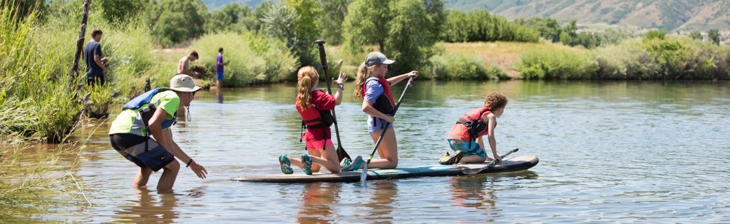 Kids stand up paddle boarding at summer camp