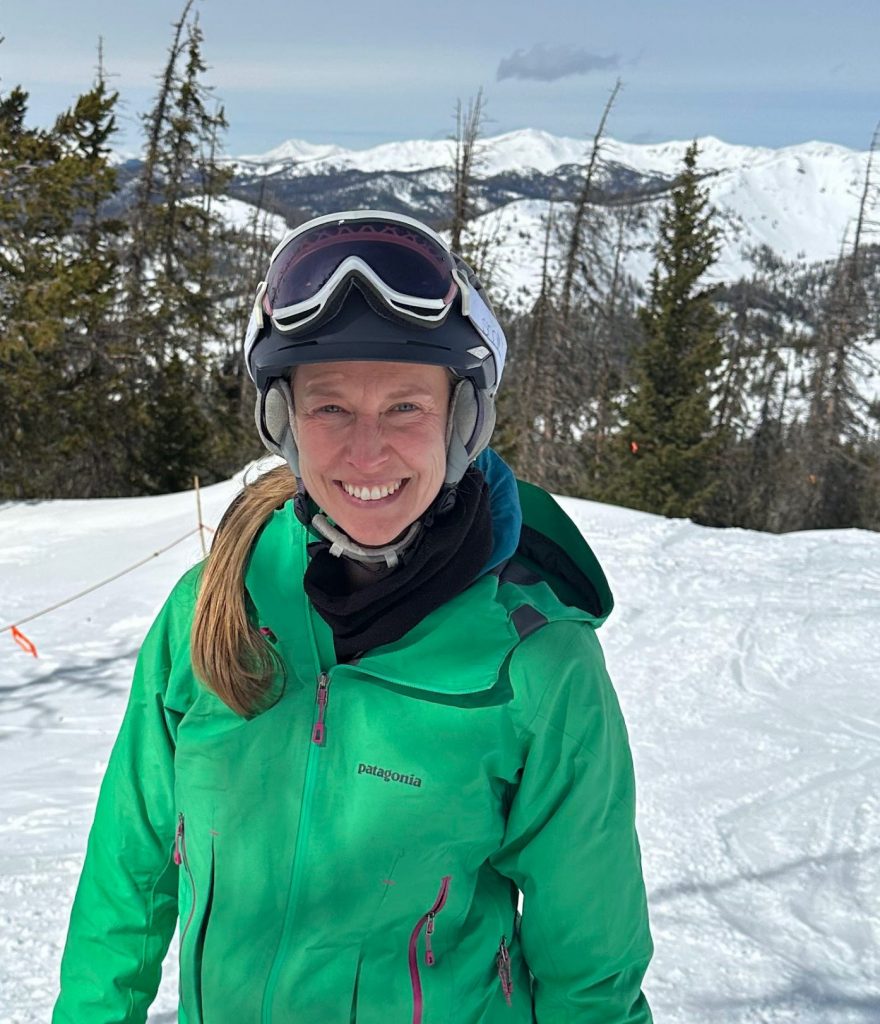 Camp staff member smiling in ski gear surrounded by snow