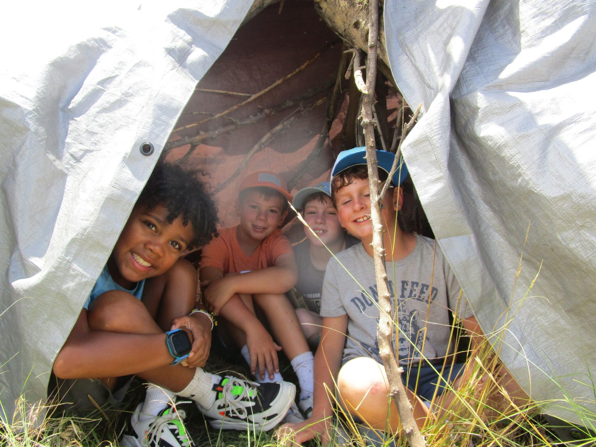 Boys smiling in a homemade tent at summer camp