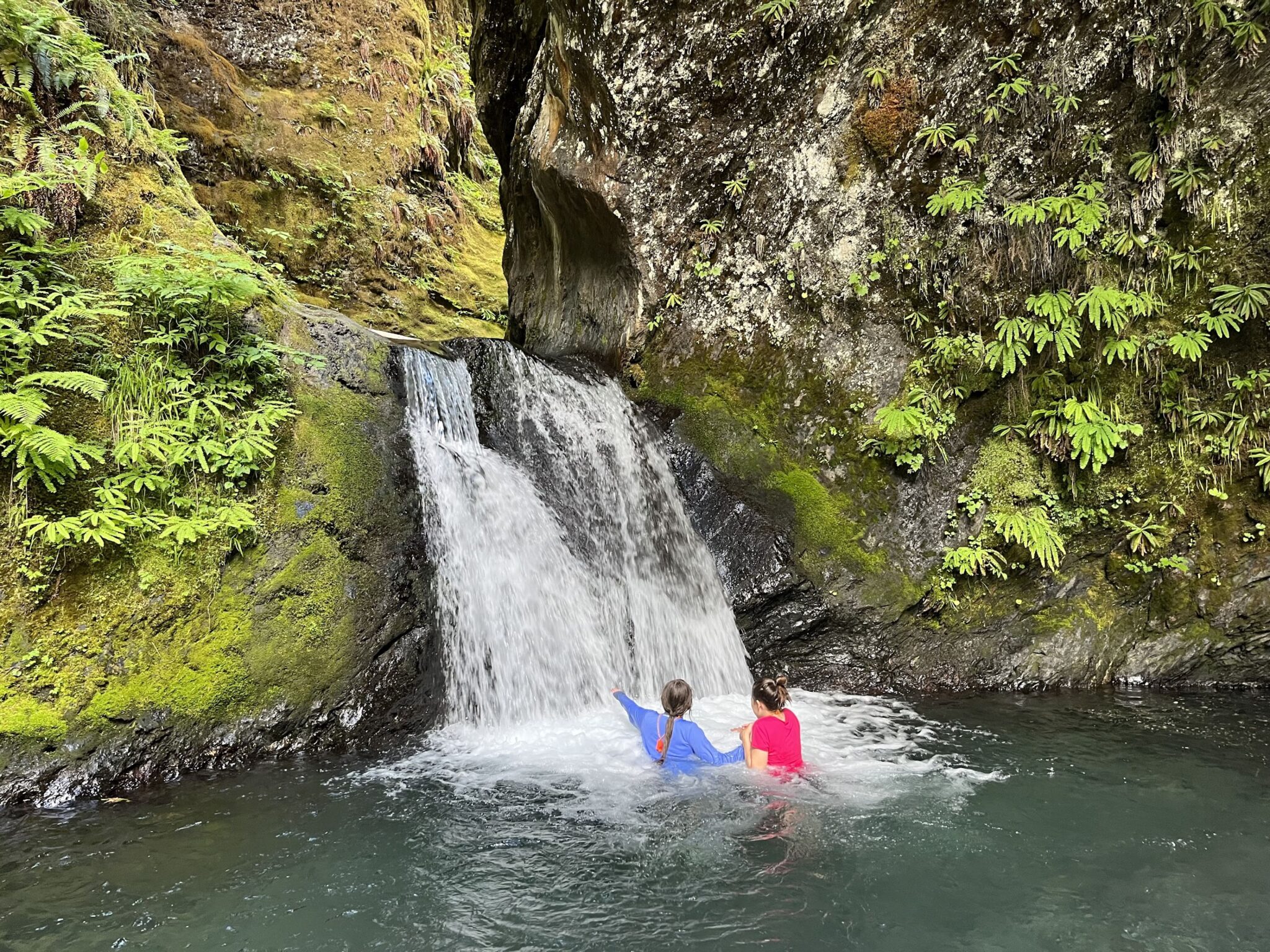Girls swimming in front of a waterfall